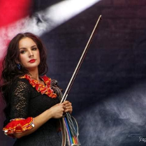 Kobieta z instrumentem stojąca na scenie.