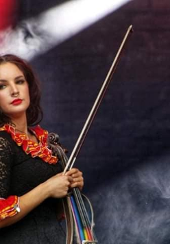 Kobieta z instrumentem stojąca na scenie.