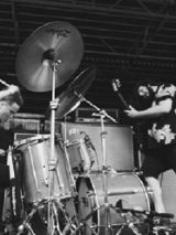 Perkusista i gitarzysta grający na scenie.