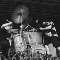 Perkusista i gitarzysta grający na scenie.