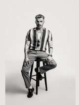 Mężczyzna siedzi na krześle na czarno-białym zdjęciu.