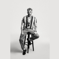 Mężczyzna siedzi na krześle na czarno-białym zdjęciu.