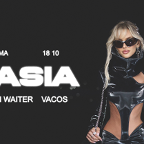 Blond kobieta w lateksowym kostiumie i ciemnych okularach, po lewej informacje o jej koncercie.