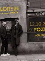 Obraz przedstawia dwóch mężczyzn stojących na chodniku przed ceglanym murem. Na ścianie znajduje się napis "LOREIN" z żółtymi literami. Jest też napis "COFFEE" i kolejny napis "12.10.2024 // POZNAN // POD MINOGĄ // UGP". Mężczyźni mają na sobie zwykłe ubrania i wydają się patrzeć na coś poza kamerą. Obraz jest czarno-biały, a oświetlenie jest stosunkowo słabe.