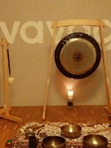 Zdjęcie przedstawia kilka mis i gongi, stojące na tle ściany z napisem Lovayoga. Scenę oświetla kilka ustawionych na podłodze świeczek.