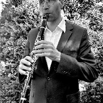 Czarno-białe zdjęcie, muzyk gra na flecie w plenerze.