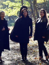 Trzy kobiety stoją na leśnej ścieżce.