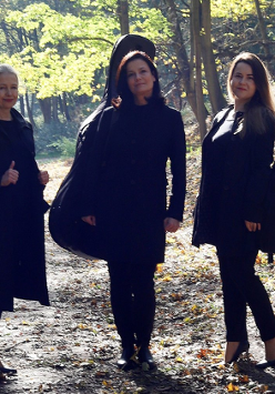 Trzy kobiety stoją na leśnej ścieżce.