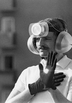 Mężczyzna w rękawiczkach, słuchawkach i głośnikiem na czole.