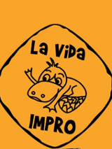 .Grafika na pomarańczowym tle przedstawia logo grupy La Vida Impro zamknięte w nieregularnym rombie o czarnym obramowaniu. Wewnątrz znajduje się rysunkowa postać uśmiechniętego dziobaka oraz napisy "La Vida" u góry i "IMPRO" u dołu.