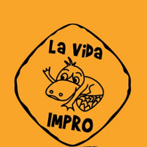 .Grafika na pomarańczowym tle przedstawia logo grupy La Vida Impro zamknięte w nieregularnym rombie o czarnym obramowaniu. Wewnątrz znajduje się rysunkowa postać uśmiechniętego dziobaka oraz napisy "La Vida" u góry i "IMPRO" u dołu.