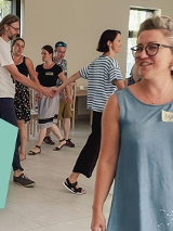 Kilkanaście osób trzymajacych sie za ręce, które ida jaden za drugim