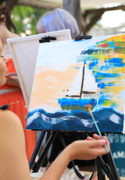 Kobieta przed sztalugą, maluje obraz.