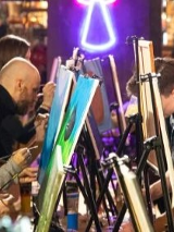 Zdjęcie, grupa osób stoi przed sztalugami i maluje obrazy.