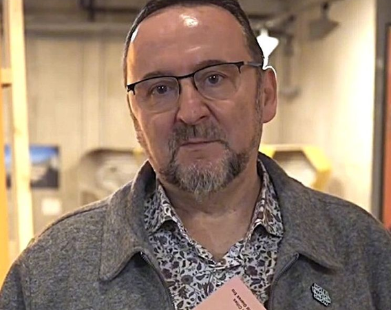 Mężczyna w okularach trzyma w rękach książkę.