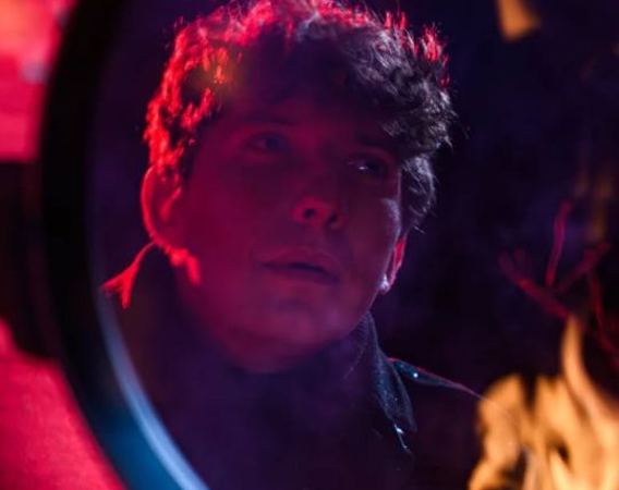 Mężczyzna przegląda się w lustrze, u dołu lustra płonie ogień.