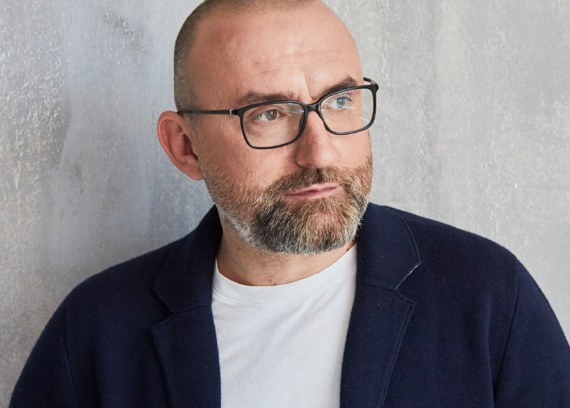 Mężczyzna w okularach, broda, wąsy, patrzy z ukosa w bok