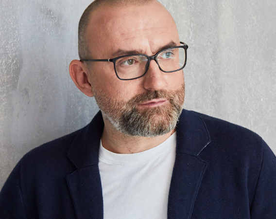 Mężczyzna w okularach, broda, wąsy, patrzy z ukosa w bok