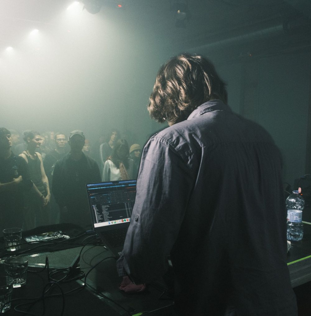 Mężczyzna za konsoletą gra koncert dla publiczności w klubie.
