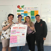 Czworo młodych osób stoi przed tablicą, trzymając w dłoniach dużą kartkę z ręcznymi zapiskami.