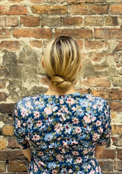 Kobieta stoi zwrócona przodem do ceglanej ściany.