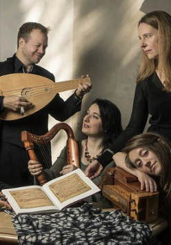 Na zdjęciu grupa muzyków. Znajdują się wokół stołu. Ktoś gra w zamyśleniu - a ktoś patrzy w dal.