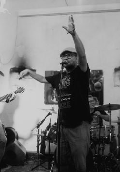 Czarnobiałe zdjęcie zespołu muzycznego składającego się z pięciu mężczyzn. Jeden śpiewa, dwóch gra na gitarach. Z tyłu jeden mężczyzna gra na perkusji a drugi na pianinie elektrycznym.