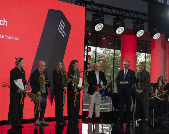Nominowani stoją na scenie, wszyscy trzymają kwiaty i dyplomy.