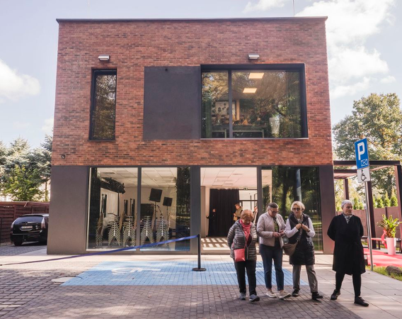 DK AZK, miejski dom kultury, fot. Grzegorz Dembiński Nowoczesny budynek jednopiętrowy, przed nim ludzie