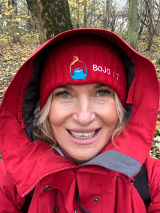 Uśmiechnięta kobieta ubrana w czerwoną czapkę i czerwony kaptur.