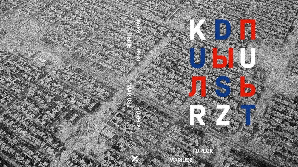 Fragment okładki, szara, sprawia wrażenie zakurzonej, wygląda jak panorama zniszczonego miasta. Tytuł napisany biało-czerwono-niebieskimi literami.