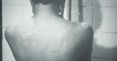 Na okładce tomiku czarno-białe zdjęcie nagiego, stojącego tyłem do fotografa człowieka pod prysznicem. Zapis autora i tytułu czerwoną czcionką.