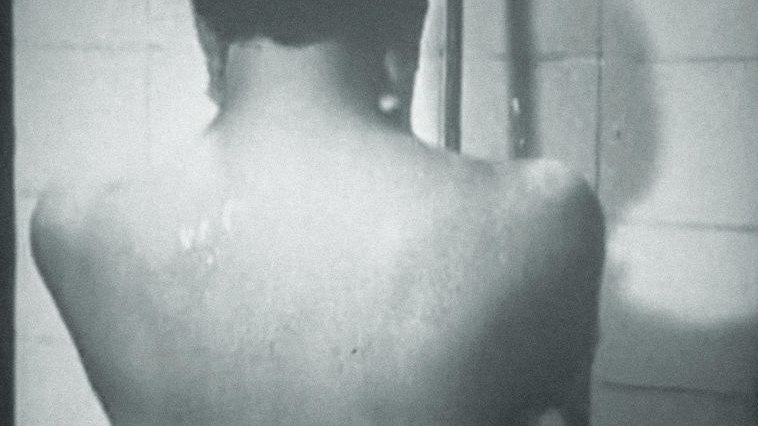 Na okładce tomiku czarno-białe zdjęcie nagiego, stojącego tyłem do fotografa człowieka pod prysznicem.