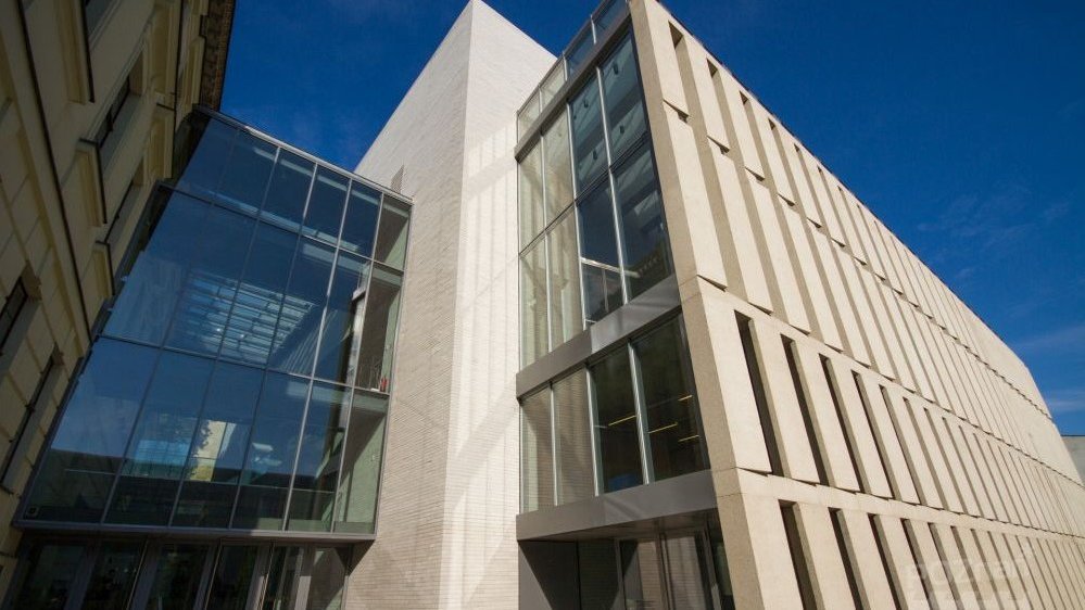 Budynek nowej części Biblioteki Raczyńskich sfotografowany z perspektywy żaby. U góry zdjęcia niebieskie, bezchmurne niebo.