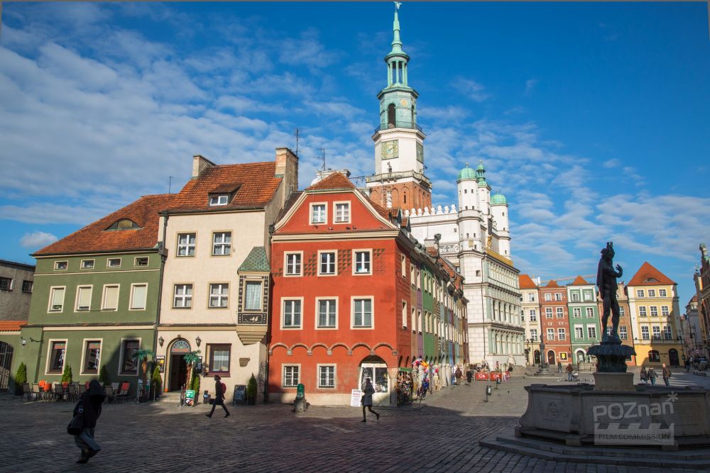 Kamienice na Starym Rynku, uchwycone w słoneczny, pogodny dzień. Za nimi ratusz, w cieniu widać także Fontannę Neptuna. - grafika artykułu