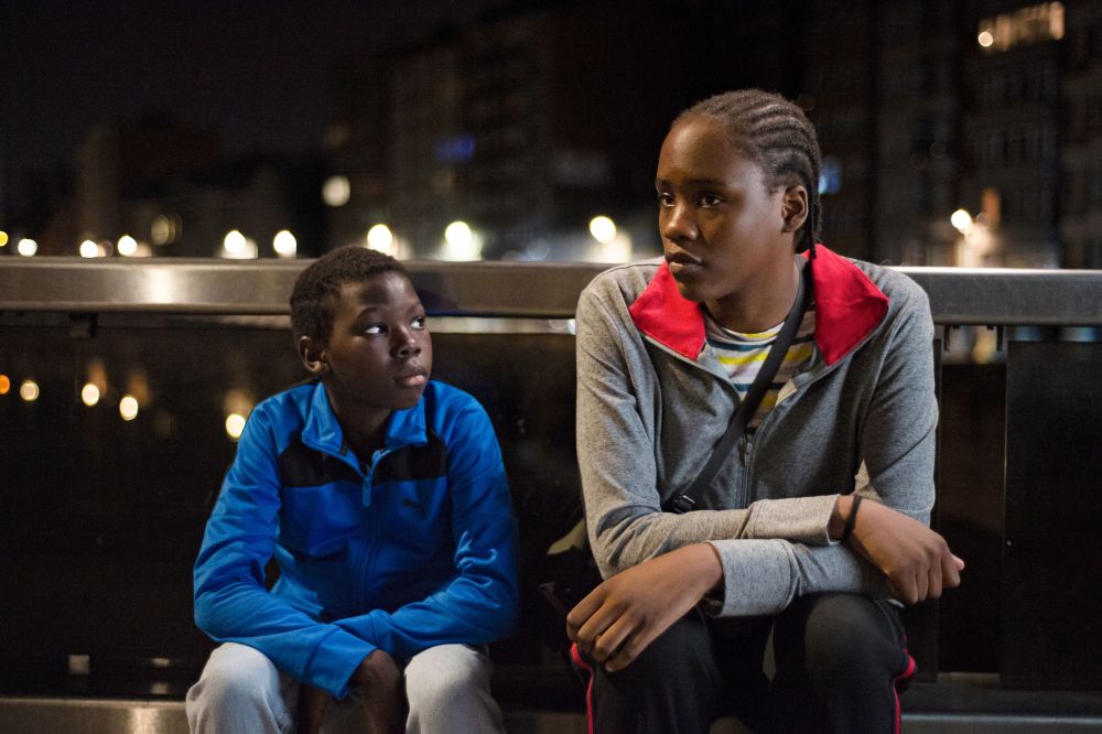 Dwójka głównych bohaterów filmu - czarnoskóra dziewczyna z warkoczykami oraz młodszy czarnoskóry chłopiec - siedzą na ławce, zamyśleni. Jest noc. - grafika artykułu