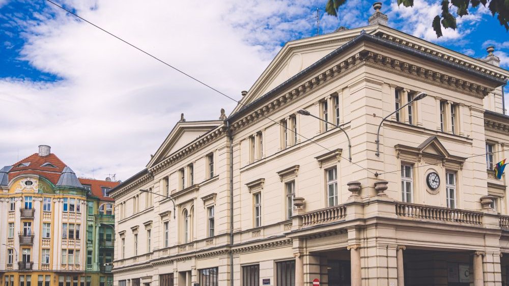 XIX-wieczny jasny budynek z zegarem na fasadzie i balkonami, znajdujący się przy ulicy Ratajczaka,