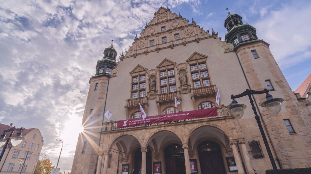 Neorenesansowy budynek o zachodzie słońca z banerem Konkursu Wieniawskiego na fasadzie.