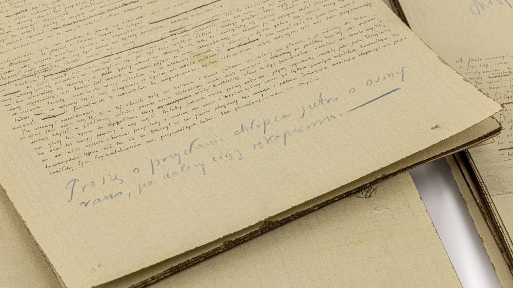 Stary, pożółkły papier, na którym widnieje zapisany odręcznie fragment powieści oraz notatki.