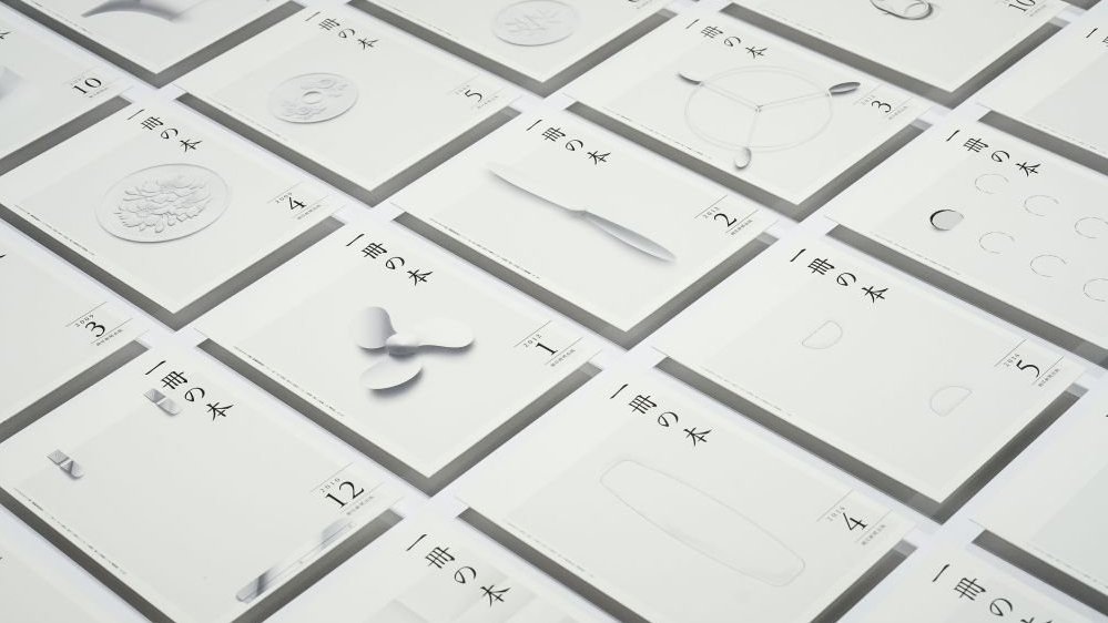 Fragment wystawy, białe kartki zapisane japońskim alfabetem, cyframi i rysunkami.