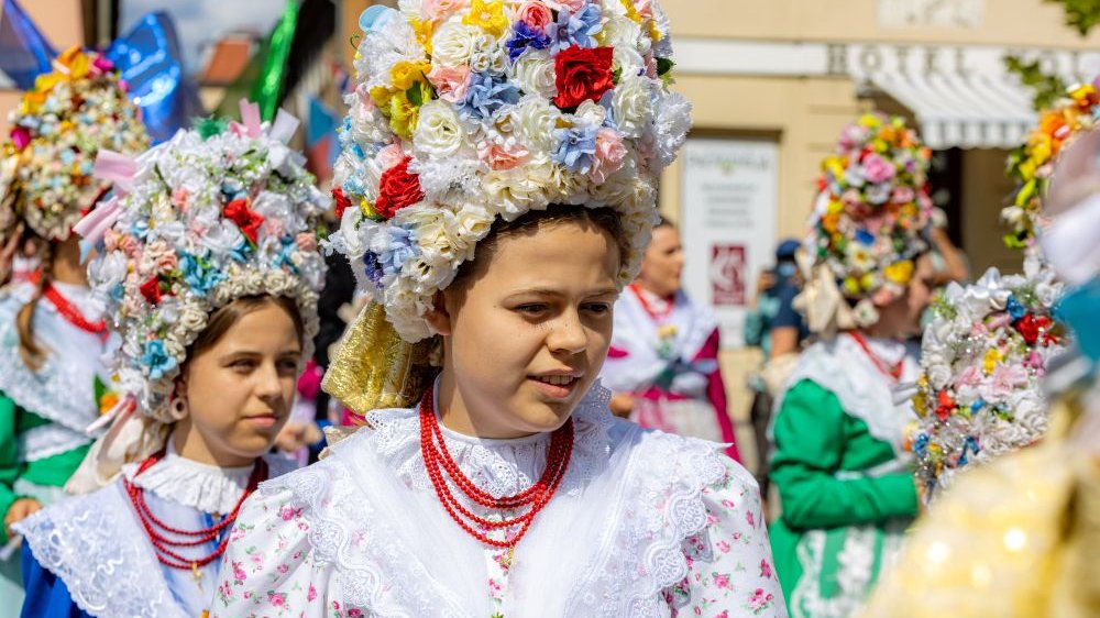 Kobiety ubrane w kolorowe stroje ludowe, na głowach mają bamberskie kornety wykonane z kwiatów, na szyjach czerwone korale.