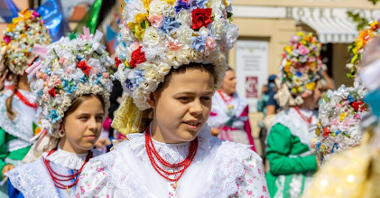 Kobiety ubrane w kolorowe stroje ludowe, na głowach mają bamberskie kornety wykonane z kwiatów, na szyjach czerwone korale.