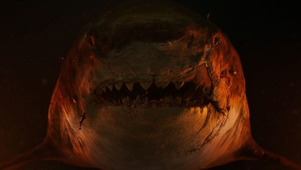 Kadr w filmu przedstawia olbrzymiego rekina, podświetlonego na pomarańczowo. - grafika artykułu