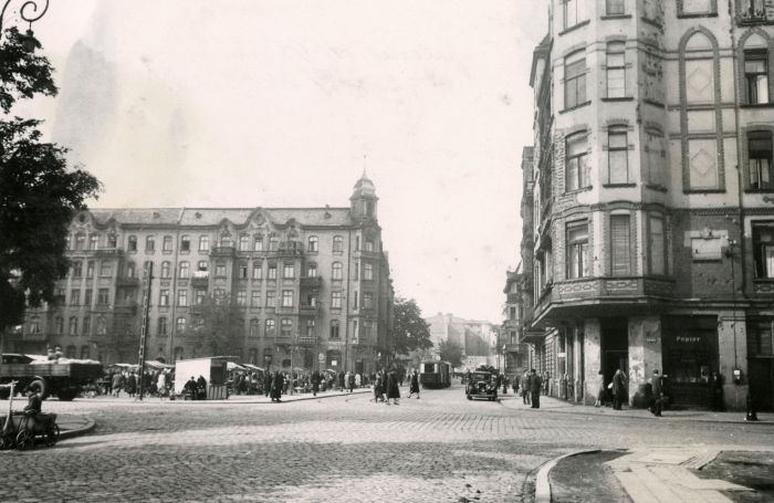 Czarno-białe zdjęcie ulicy, otoczonej kamienicami. Po lewej stronie widać rynek ze stoiskami. - grafika artykułu