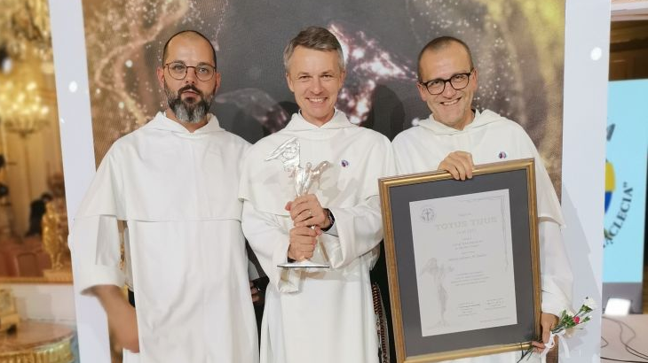 Trzech zakonników w białych habitach pozuje ze zdobytą nagrodą.