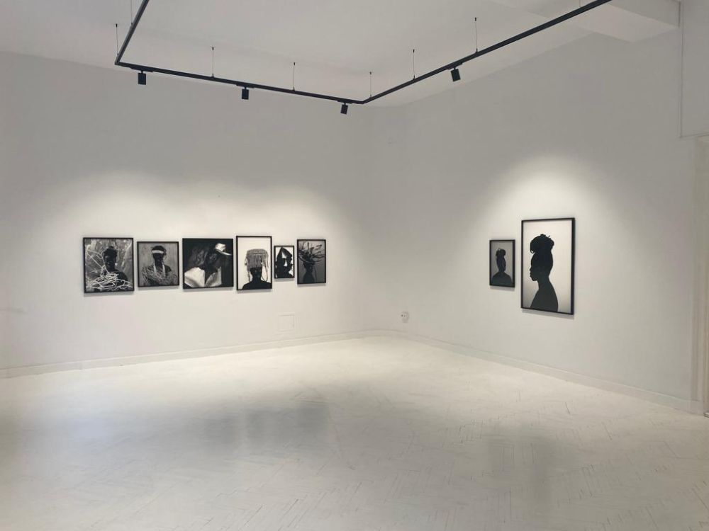 Białę wnętrze galerii z czarno-białymi, wielkoformatowymi fotografiami wiszącymi na ścianach. - grafika artykułu