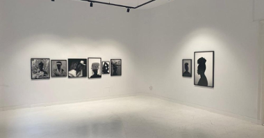 Białę wnętrze galerii z czarno-białymi, wielkoformatowymi fotografiami wiszącymi na ścianach.