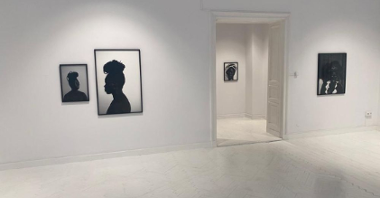 Czarno-biłe fotografie czarnoskórej kobiety na białych ścianach galerii.
