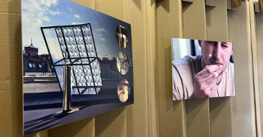 Dwa duże zdjęcia wiszące na tekturowej ścianie. Na jednym z nich panel słoneczny, na drugim mężczyzna.