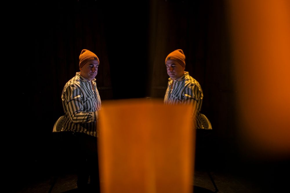 Mężczyzna w żółtej czapce i koszuli w paski odbity w lustrze. Z przodu i boku zdjęcia pomarańczowy cień. - grafika artykułu